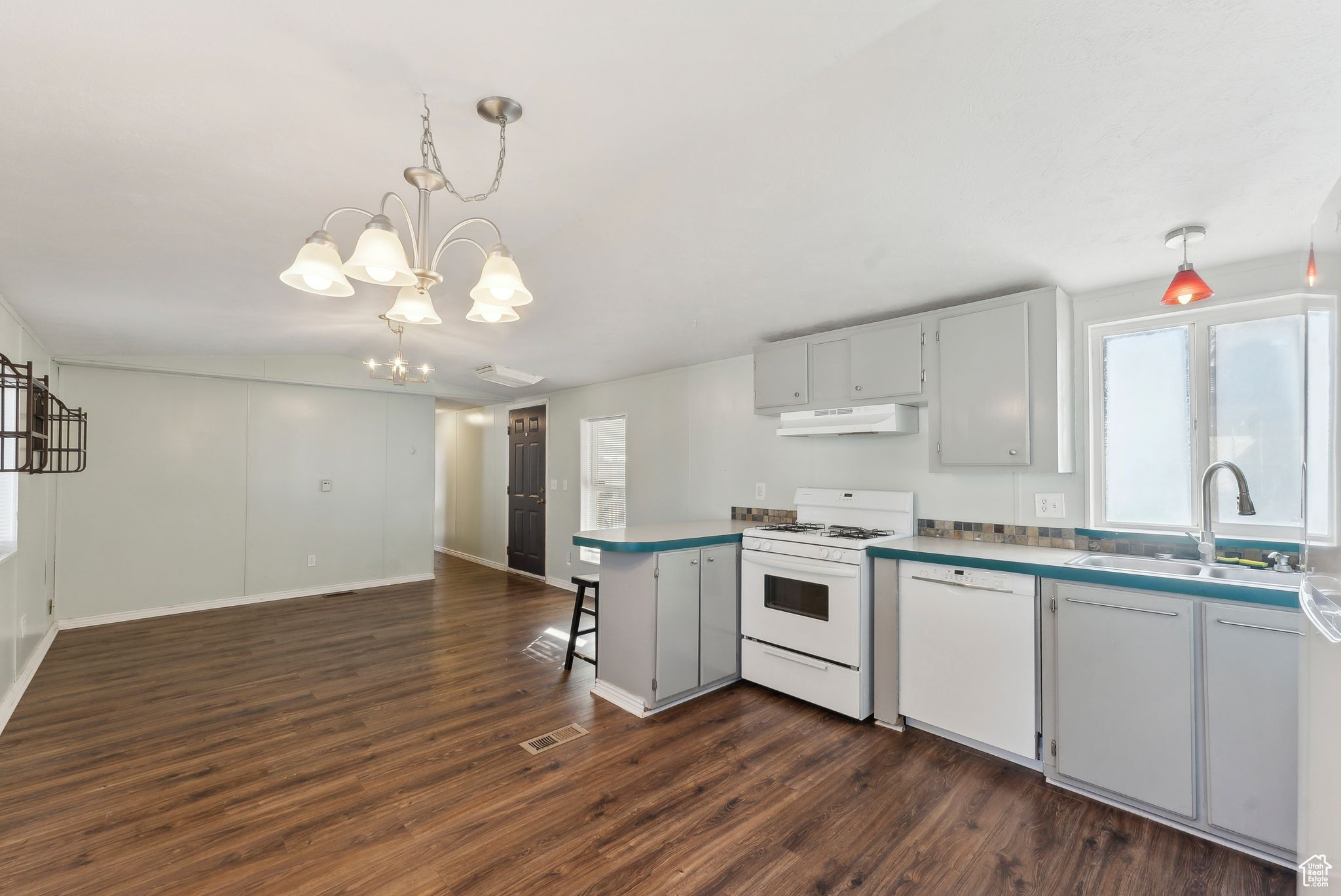 Kitchen with white appliances, sink, a notable chandelier, dark hardwood / wood-style floors, and hanging light fixtures