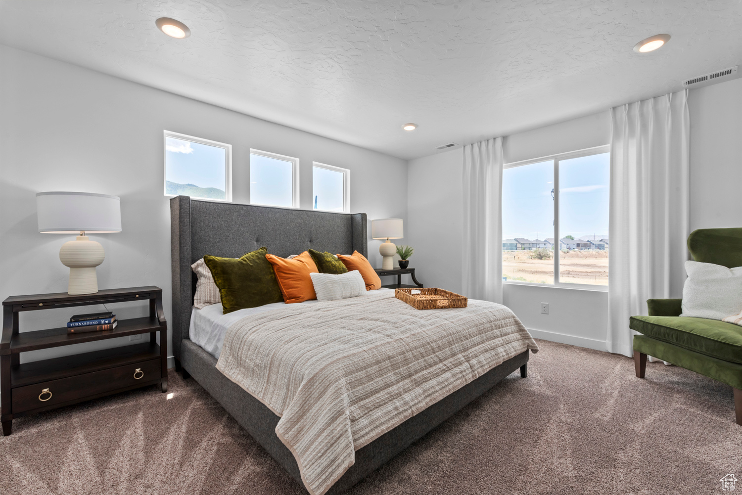 Carpeted bedroom featuring a textured ceiling and multiple windows