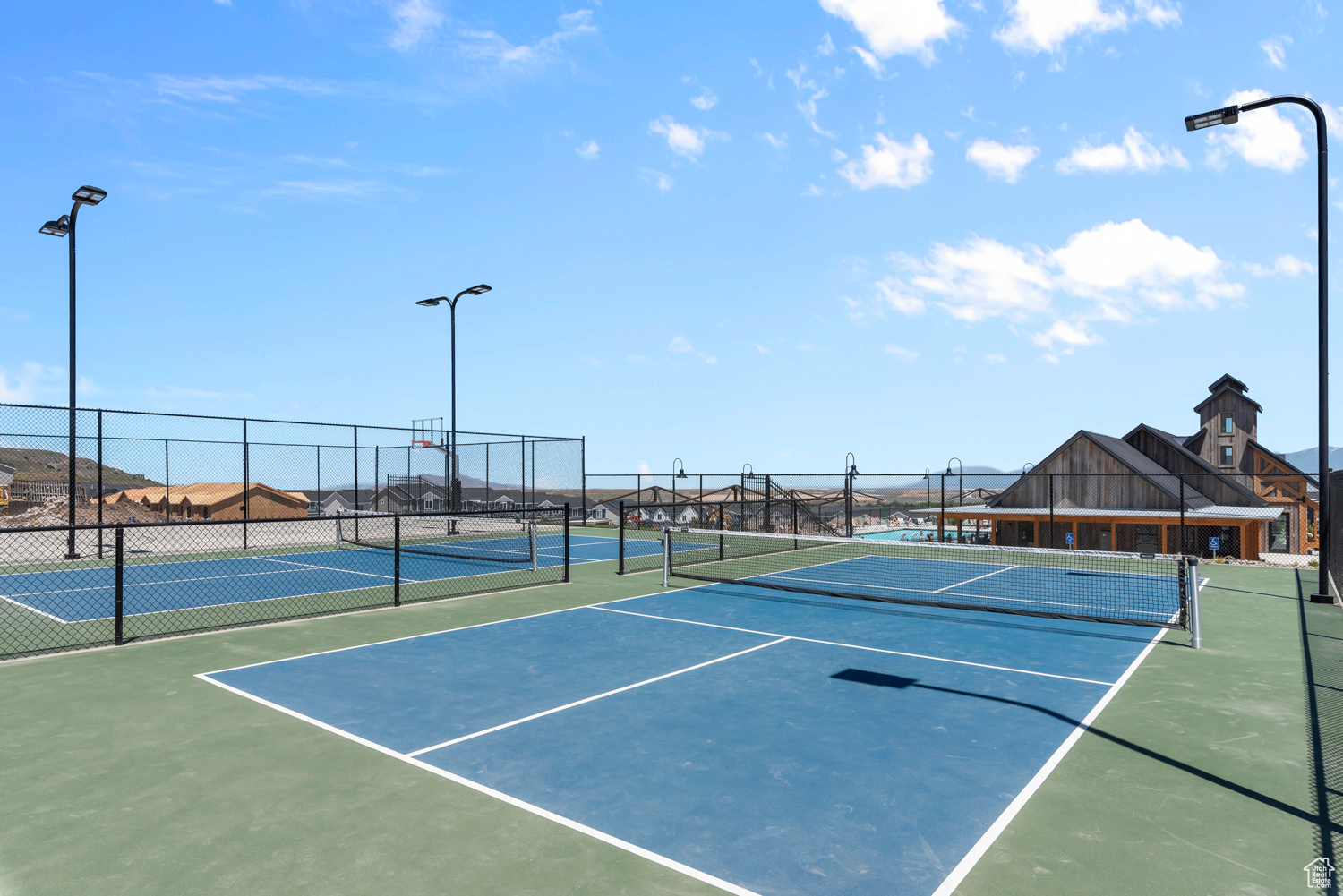 View of tennis court featuring basketball hoop