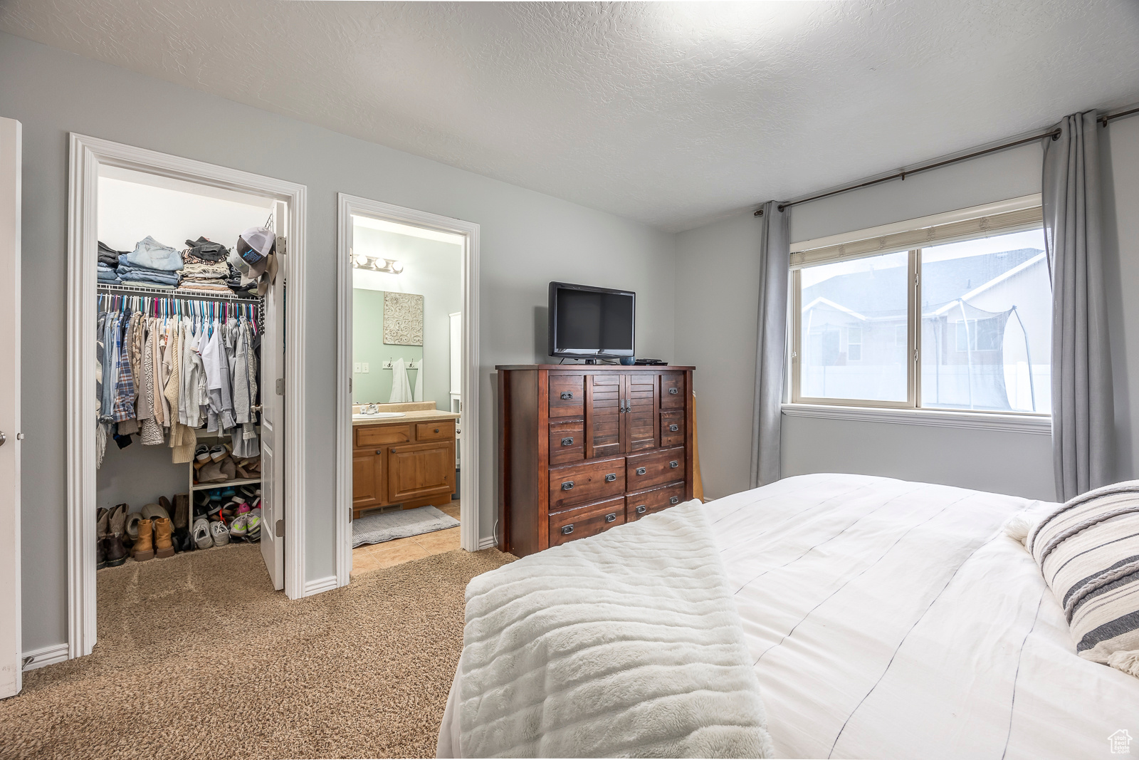 Carpeted bedroom with a walk in closet, sink, ensuite bath, a textured ceiling, and a closet