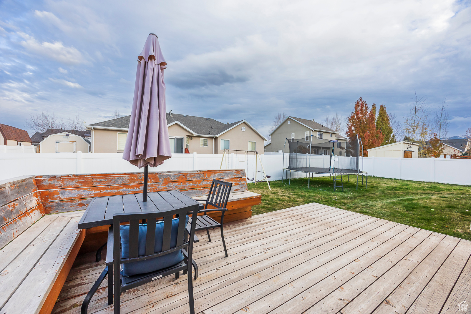 Wooden deck with a trampoline and a yard