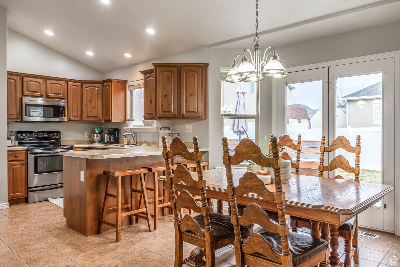 Dining room with a chandelier, light tile patterned floors, vaulted ceiling, and sink