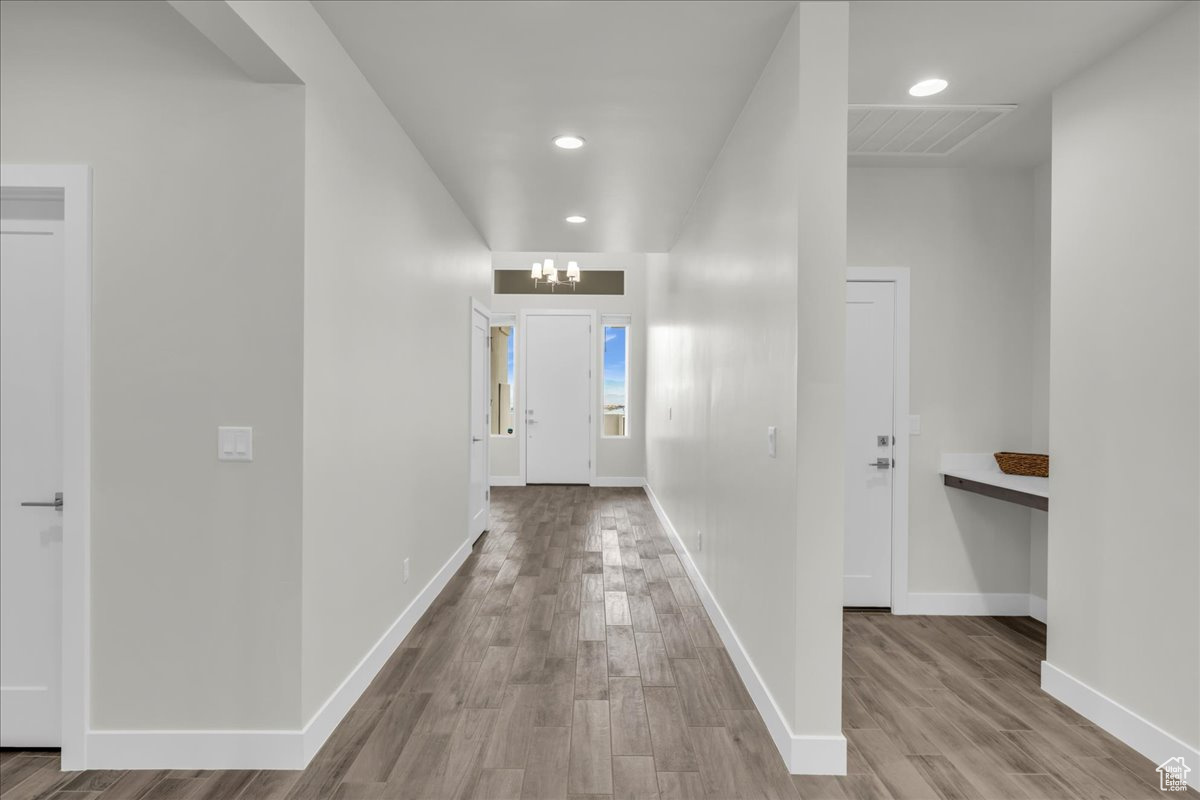 Hallway with light hardwood / wood-style floors and a chandelier