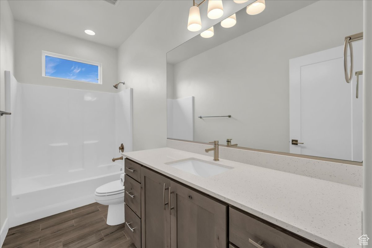 Full bathroom with shower / washtub combination, hardwood / wood-style floors, vanity, and toilet