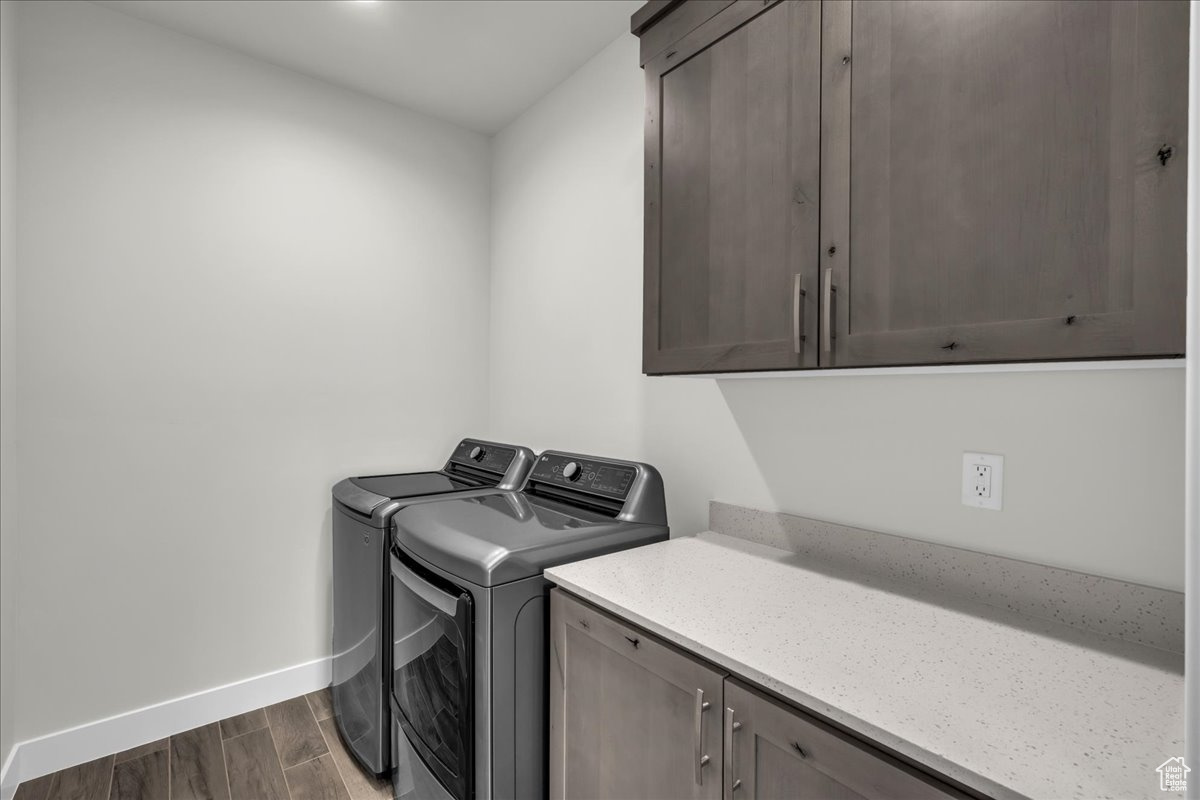 Laundry area with cabinets, independent washer and dryer, and dark wood-type flooring