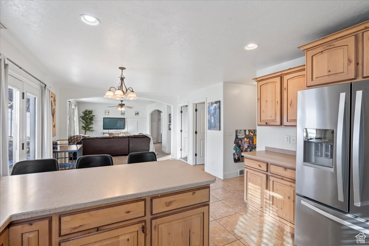 Kitchen with ceiling fan with notable chandelier, stainless steel fridge, light tile patterned floors, a textured ceiling, and decorative light fixtures