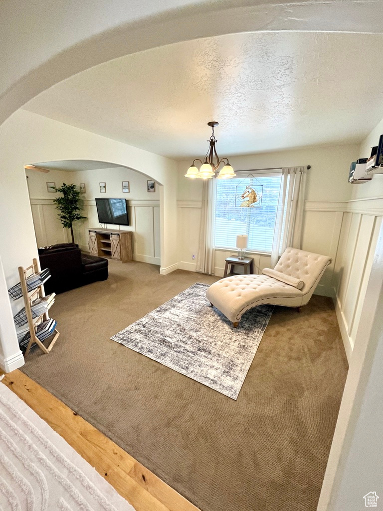 Living area with a textured ceiling, light carpet, and a chandelier