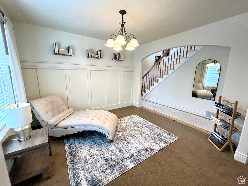 Living area featuring dark colored carpet, a wealth of natural light, and a notable chandelier