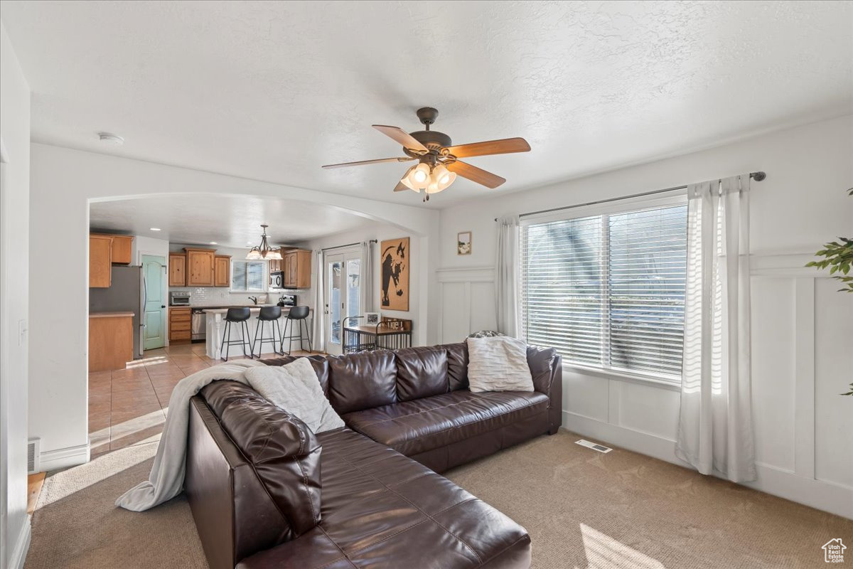 Living room featuring light carpet, ceiling fan, and a textured ceiling