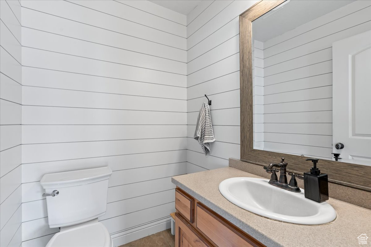 Bathroom featuring wooden walls, vanity, and toilet