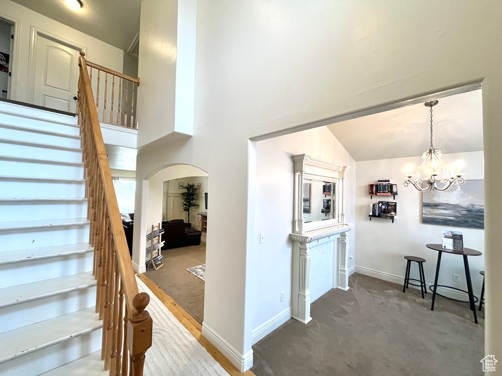 Stairway featuring carpet flooring, high vaulted ceiling, and a notable chandelier