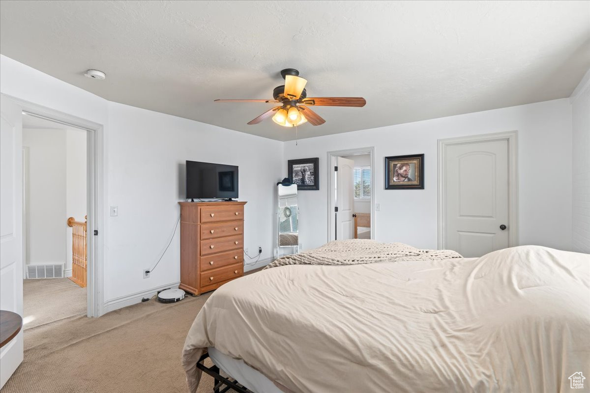 Bedroom featuring ensuite bath, ceiling fan, and light colored carpet