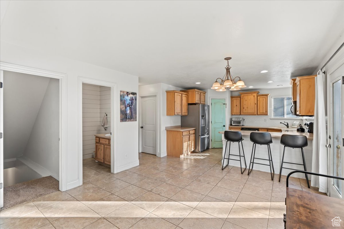 Kitchen with sink, stainless steel appliances, a notable chandelier, a kitchen bar, and light tile patterned floors