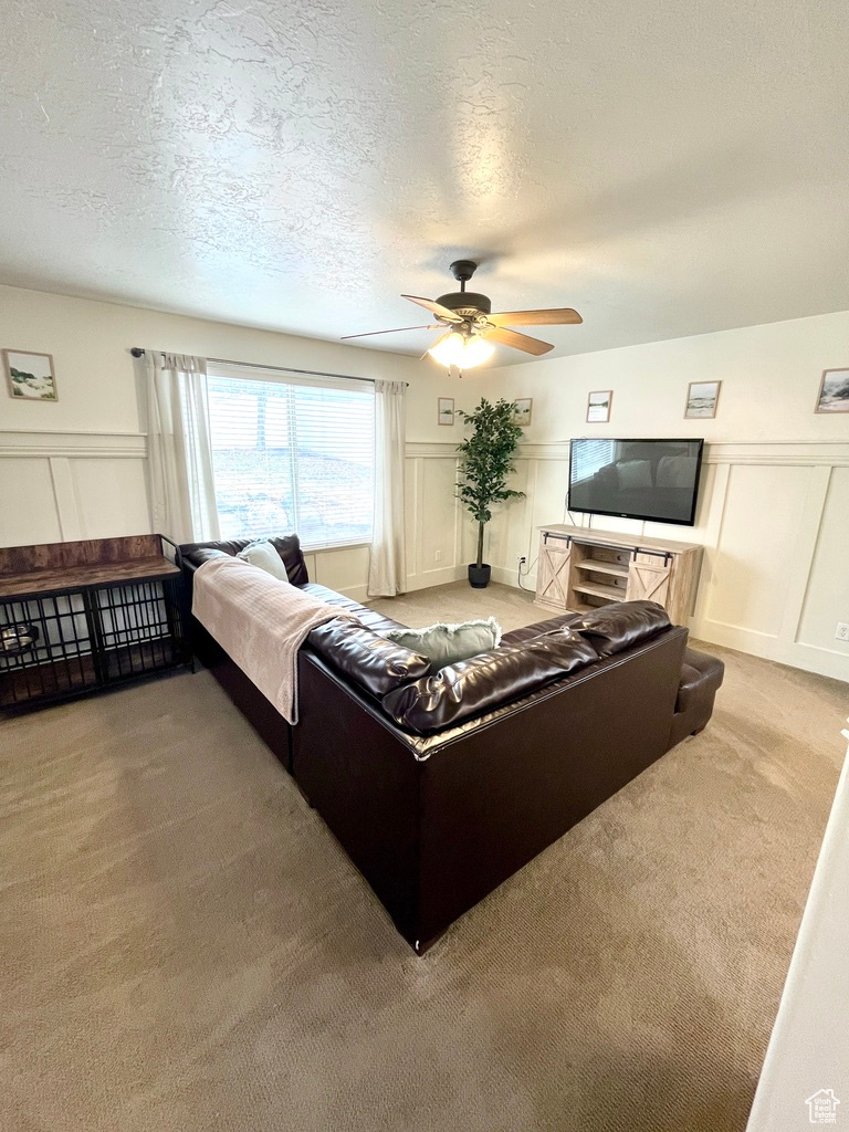 Living room with carpet flooring, ceiling fan, and a textured ceiling