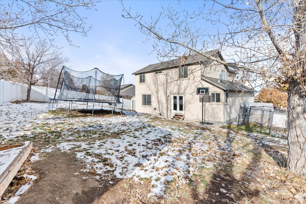 Snow covered house featuring french doors and a trampoline