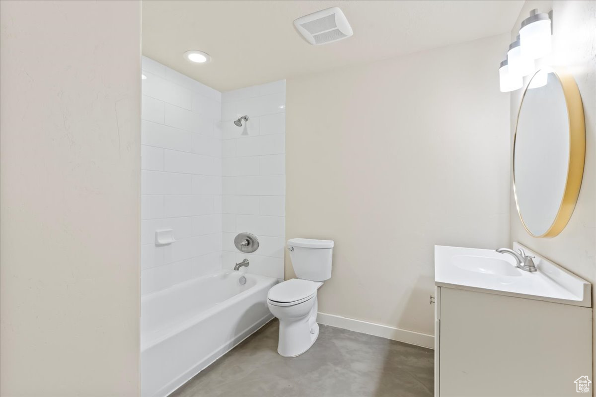 Full bathroom with vanity, tiled shower / bath, concrete flooring, and toilet