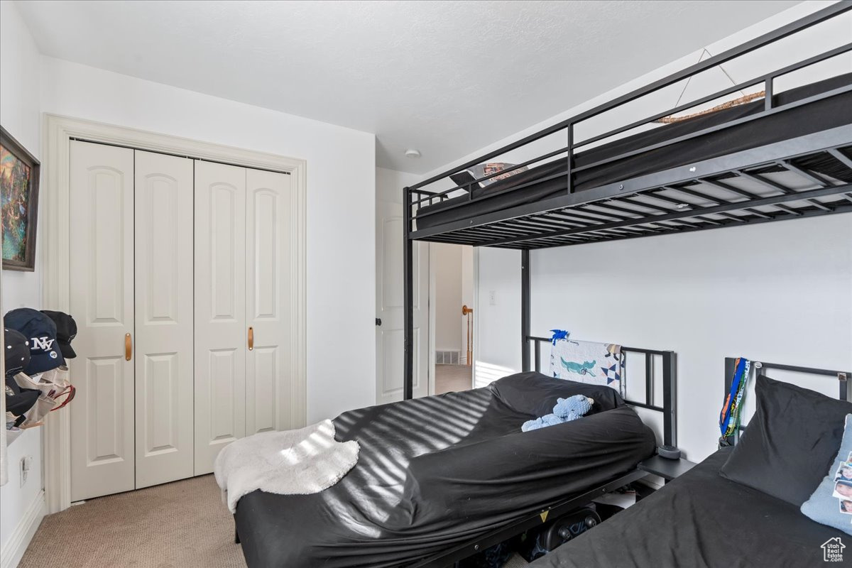 Bedroom featuring light carpet and a closet