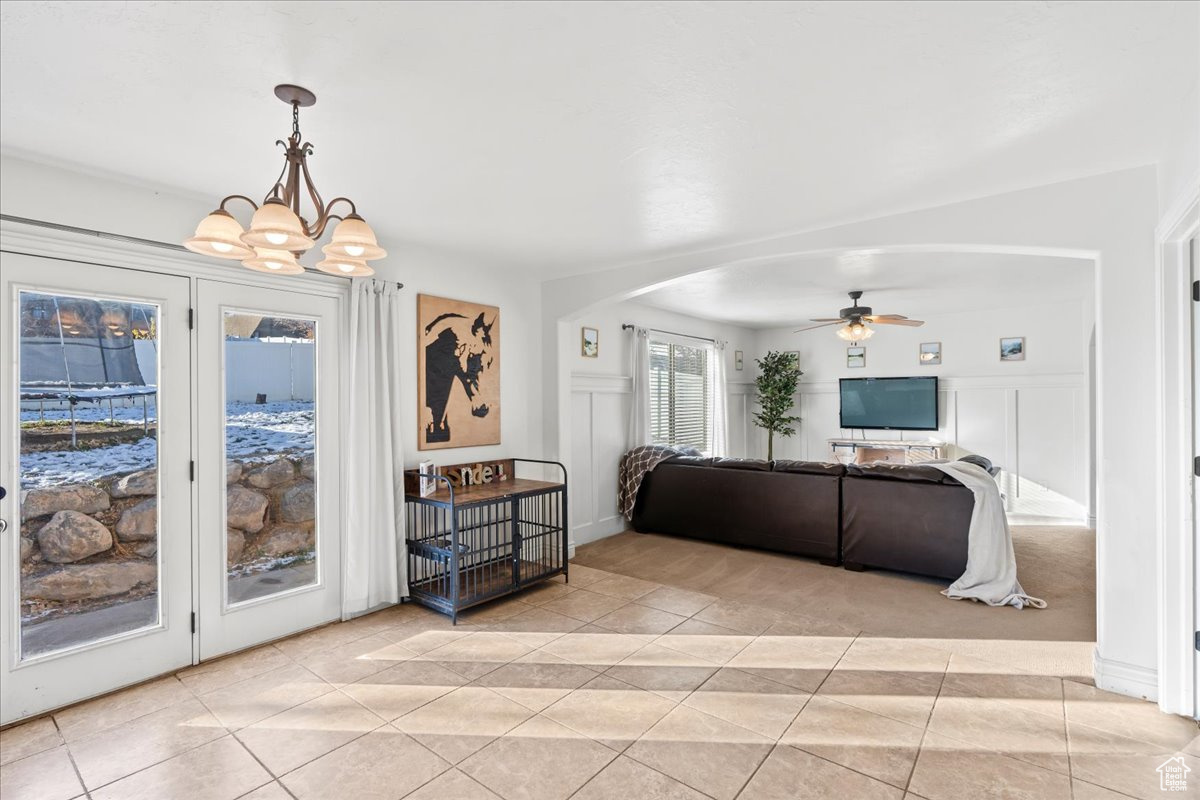 Living room featuring light tile patterned floors and ceiling fan with notable chandelier