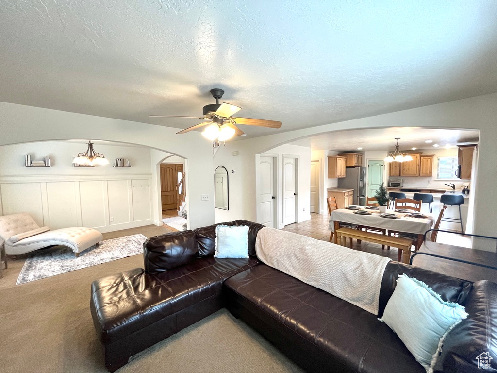 Living room featuring a textured ceiling and ceiling fan with notable chandelier