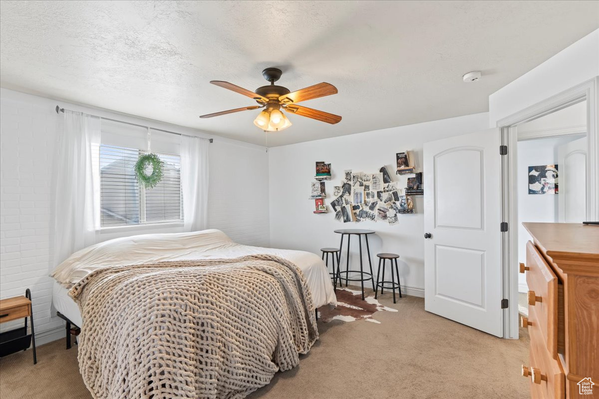 Bedroom featuring ceiling fan, light colored carpet, and a textured ceiling