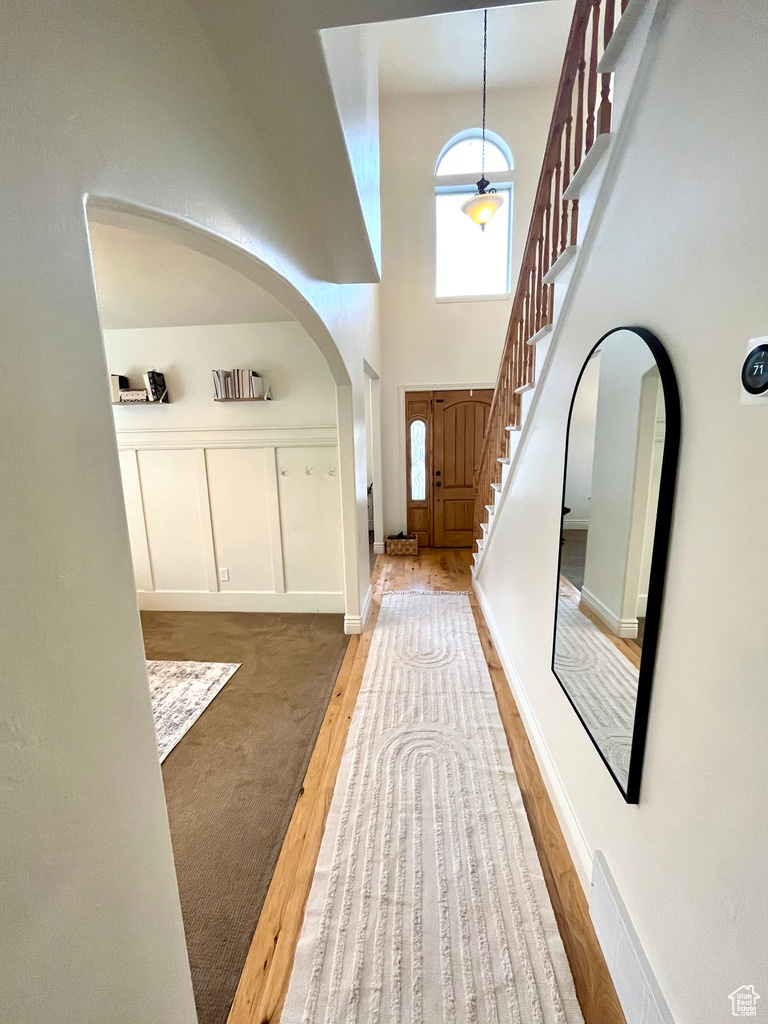 Entryway featuring hardwood / wood-style flooring, a healthy amount of sunlight, and a towering ceiling