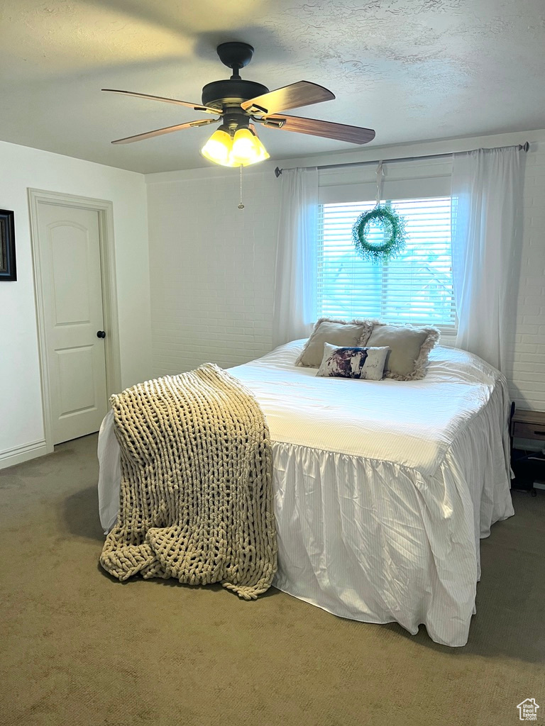 Carpeted bedroom with a textured ceiling and ceiling fan