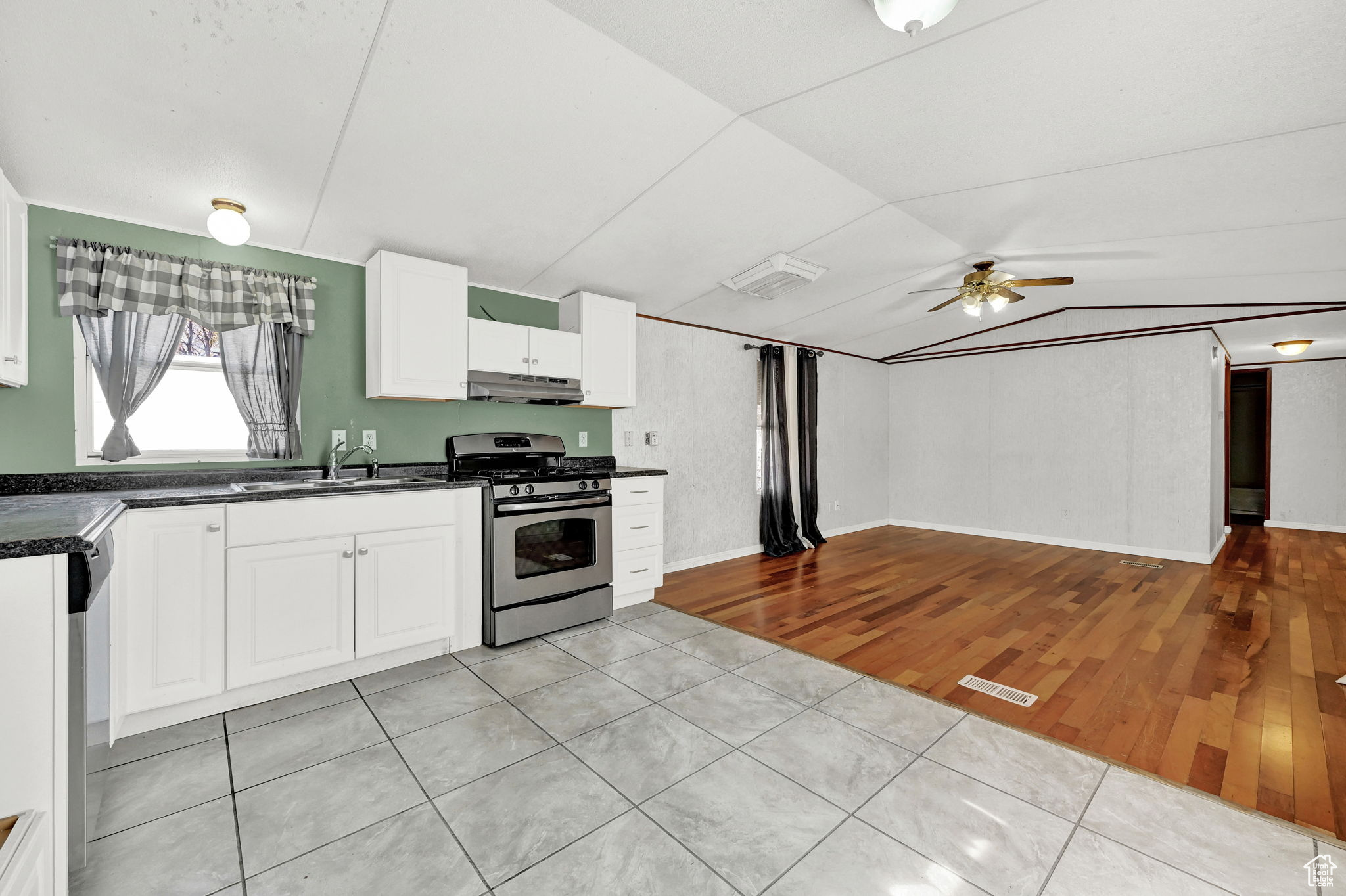 Kitchen featuring white cabinets, sink, ceiling fan, appliances with stainless steel finishes, and light hardwood / wood-style floors