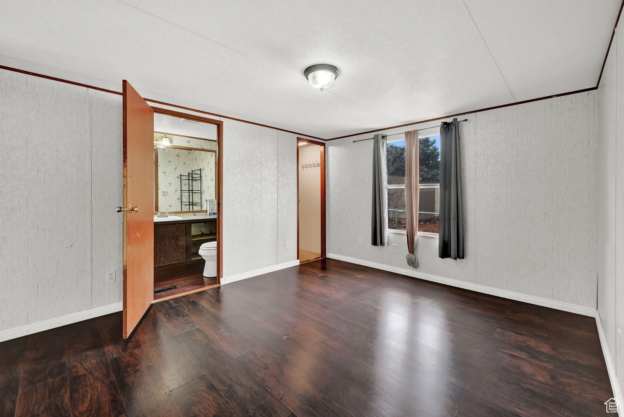 Unfurnished bedroom with hardwood / wood-style flooring, sink, a textured ceiling, and ensuite bath