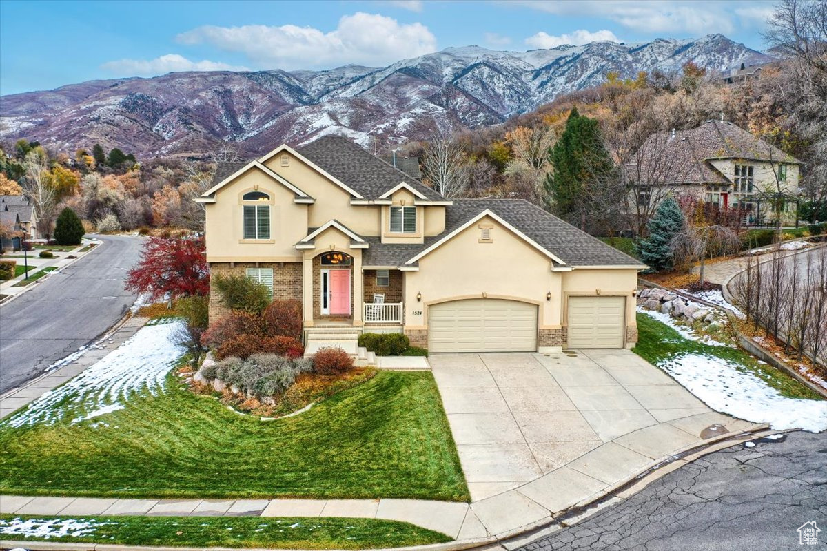 View of front of home with a mountain view, a front yard, and a garage