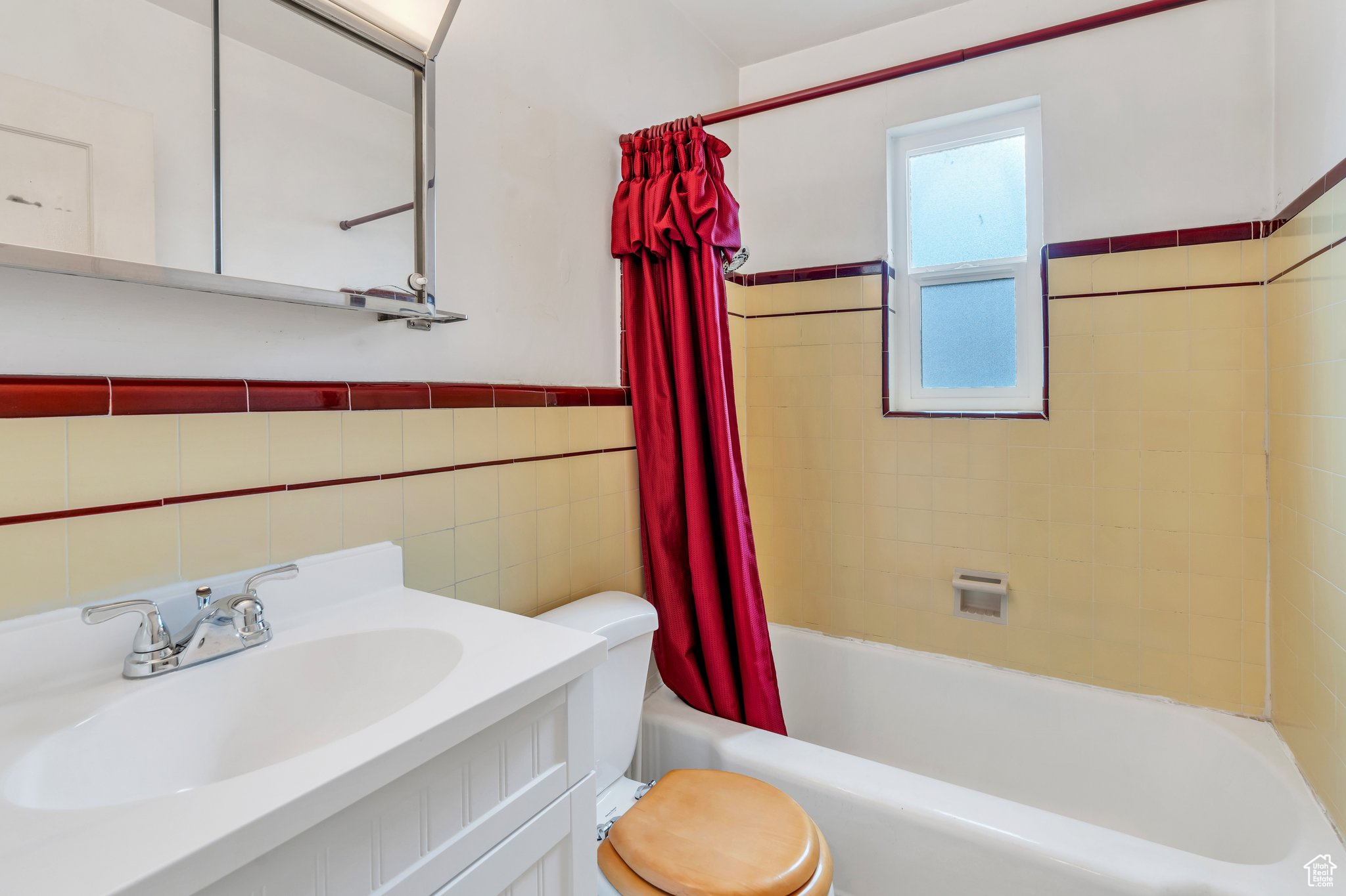 Full bathroom with vanity, shower / tub combo, tile walls, and toilet