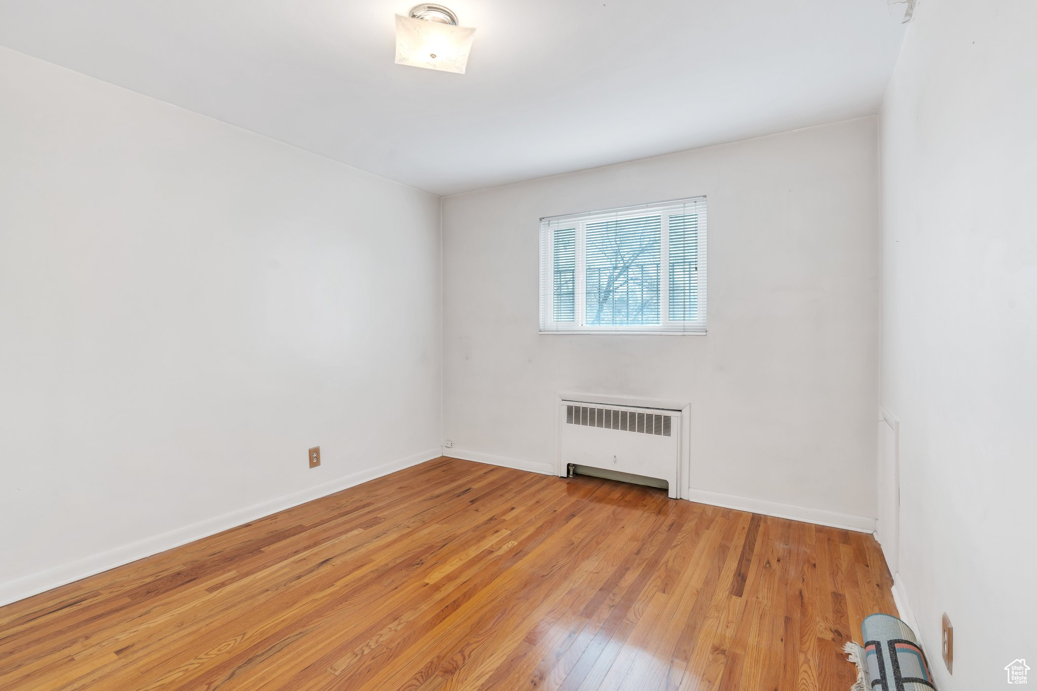 Empty room with radiator heating unit and light hardwood / wood-style floors