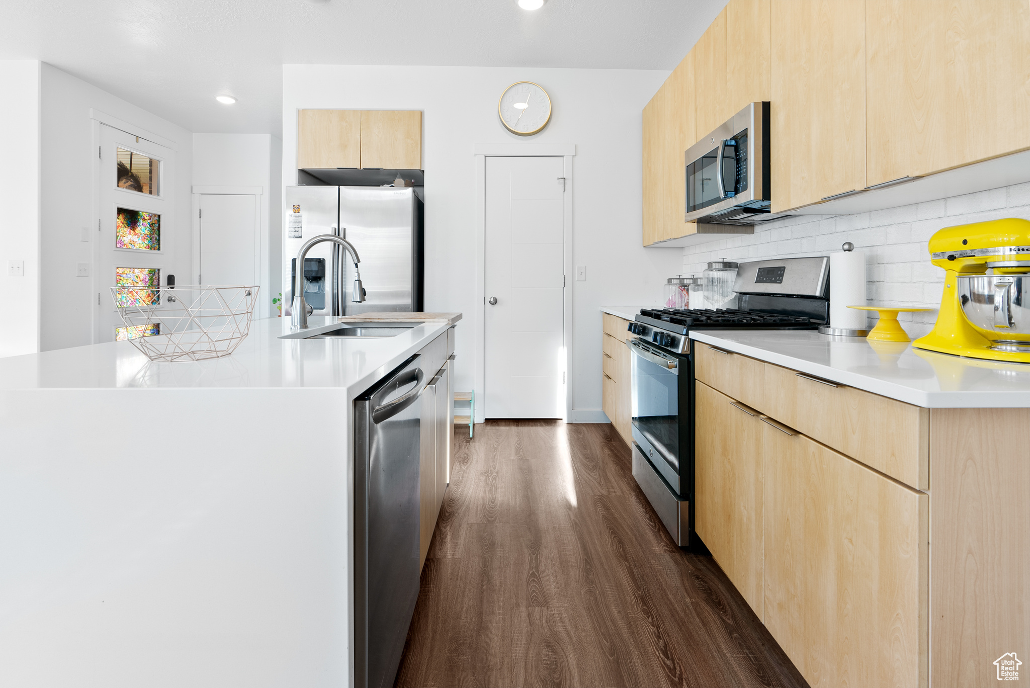 Kitchen featuring light brown cabinets, an island with sink, dark hardwood / wood-style floors, and appliances with stainless steel finishes