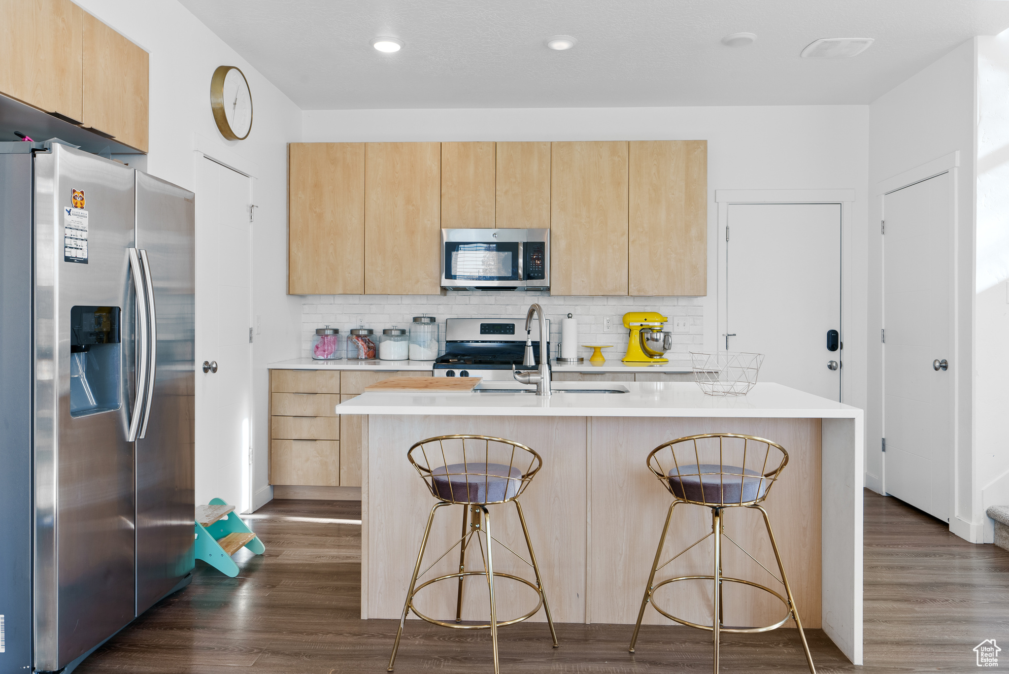 Kitchen featuring a breakfast bar area, dark wood-type flooring, a center island with sink, and stainless steel appliances