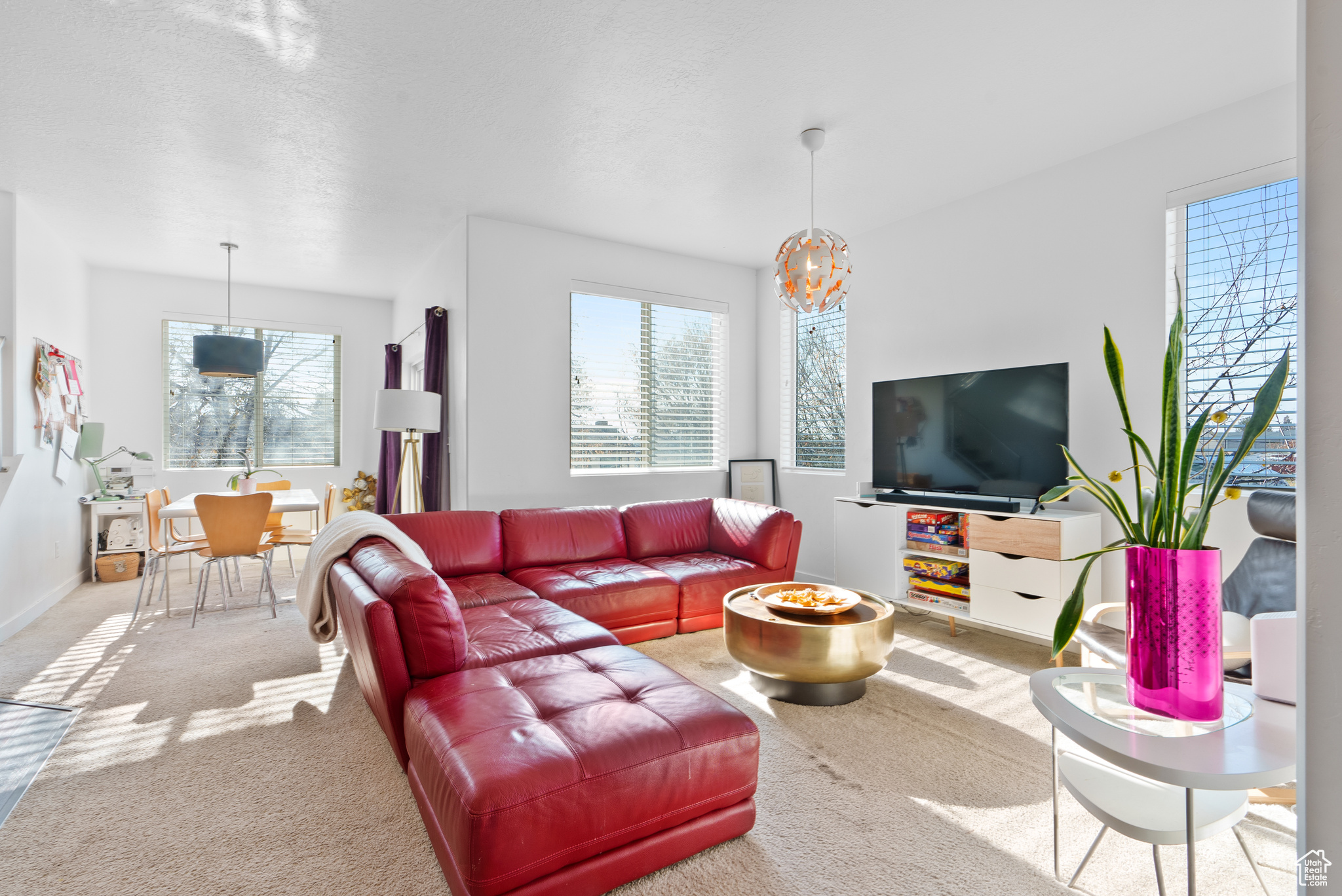 Carpeted living room with a textured ceiling, a wealth of natural light, and a chandelier