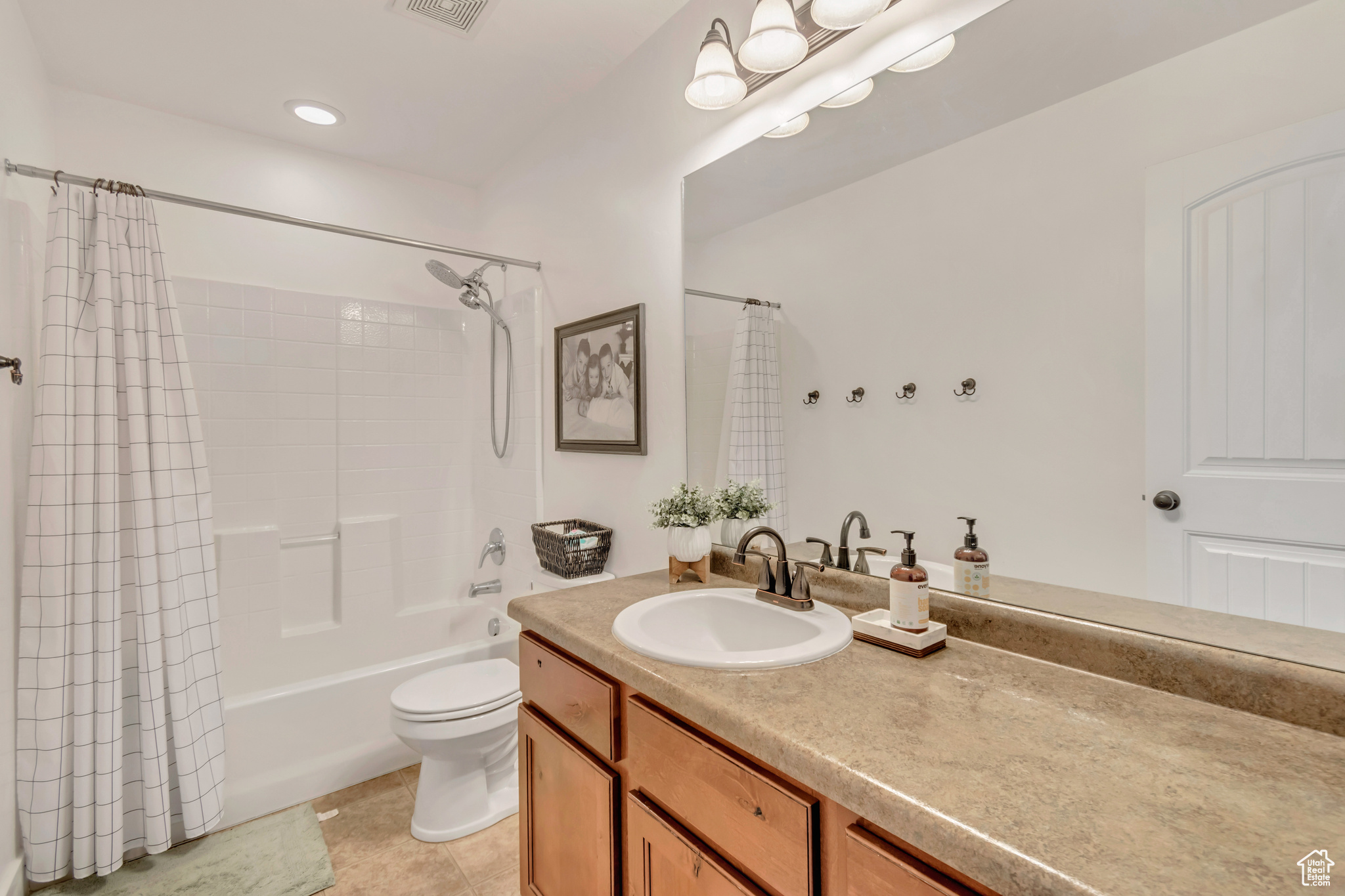 Full bathroom featuring tile patterned floors, vanity, toilet, and shower / bath combo with shower curtain