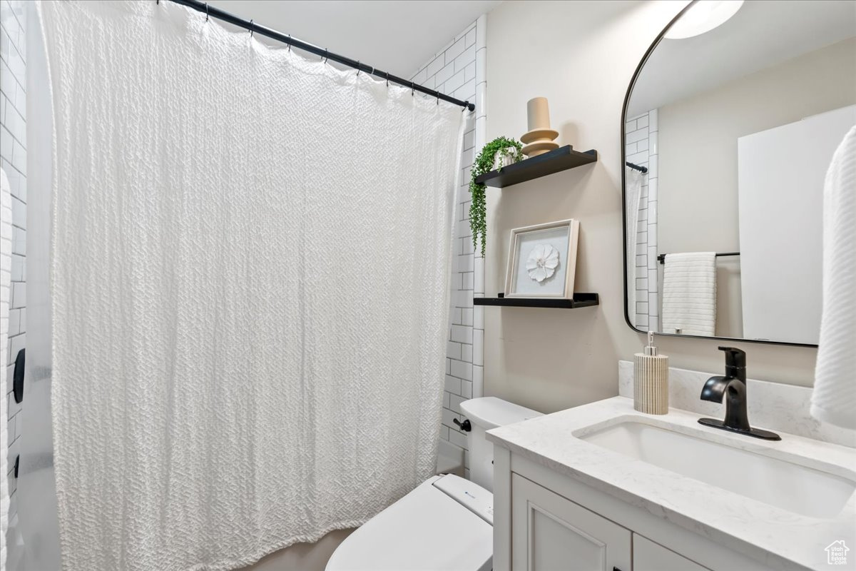 Bathroom featuring curtained shower, vanity, and toilet