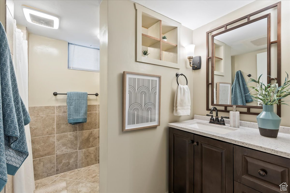 Bathroom with vanity, tile patterned floors, and tile walls