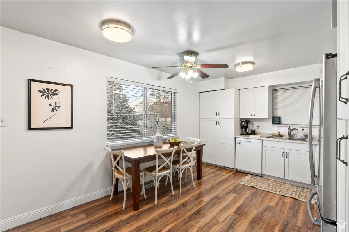 Kitchen with dishwasher, sink, dark hardwood / wood-style floors, stainless steel fridge, and white cabinetry