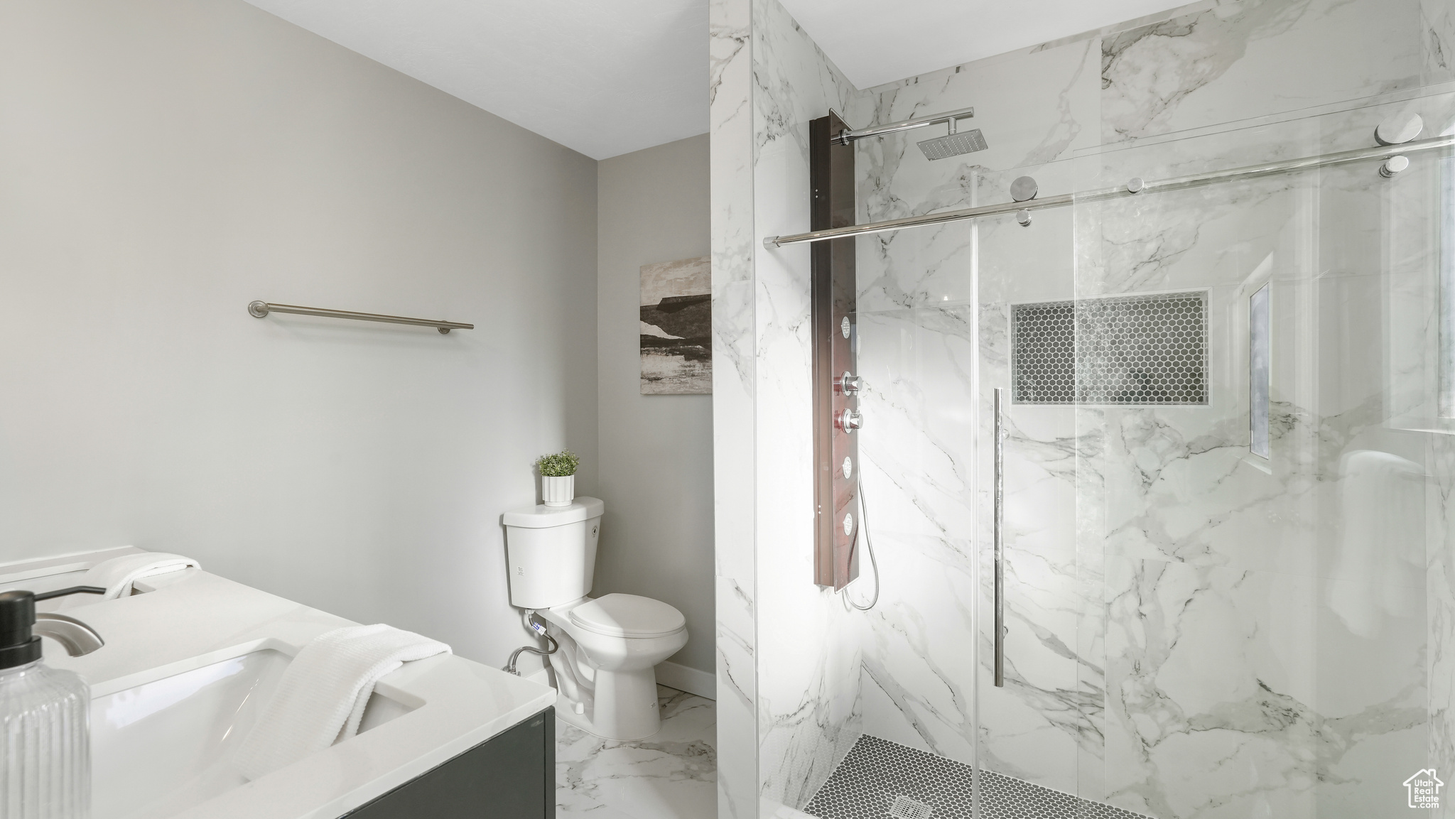 Bathroom featuring vanity, toilet, and tiled shower