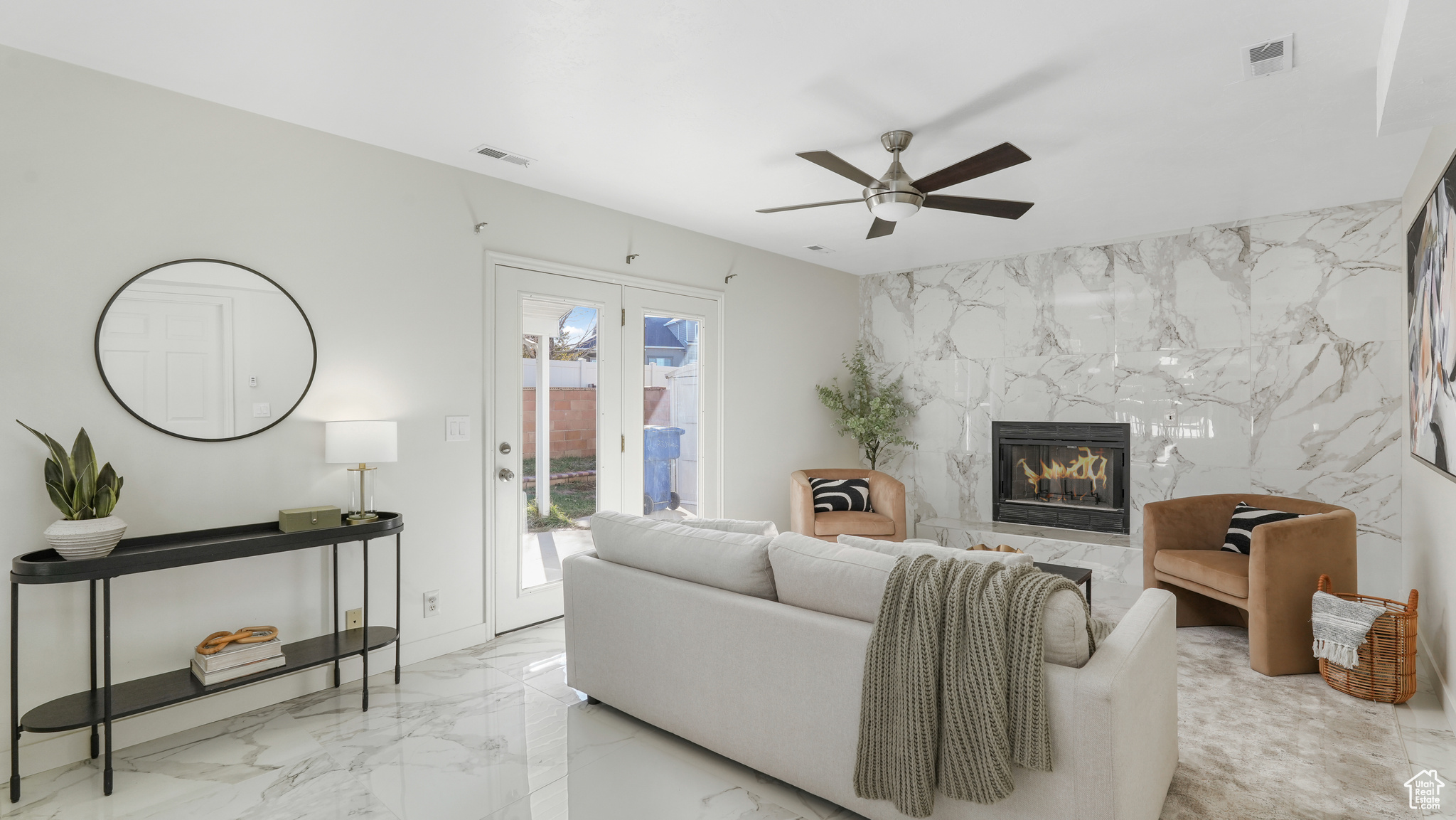 Living room with a premium fireplace, ceiling fan, and tile walls