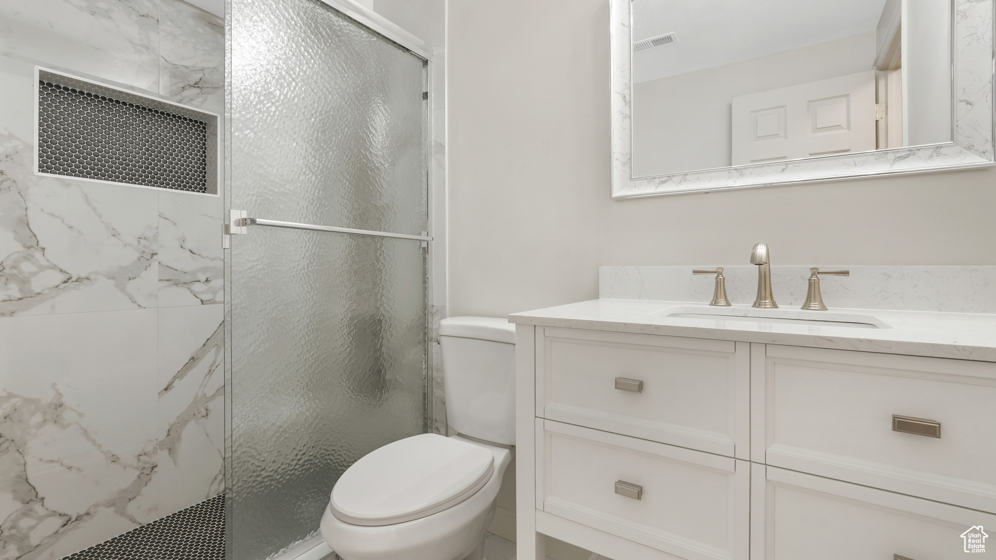 Bathroom featuring toilet, vanity, and walk in shower