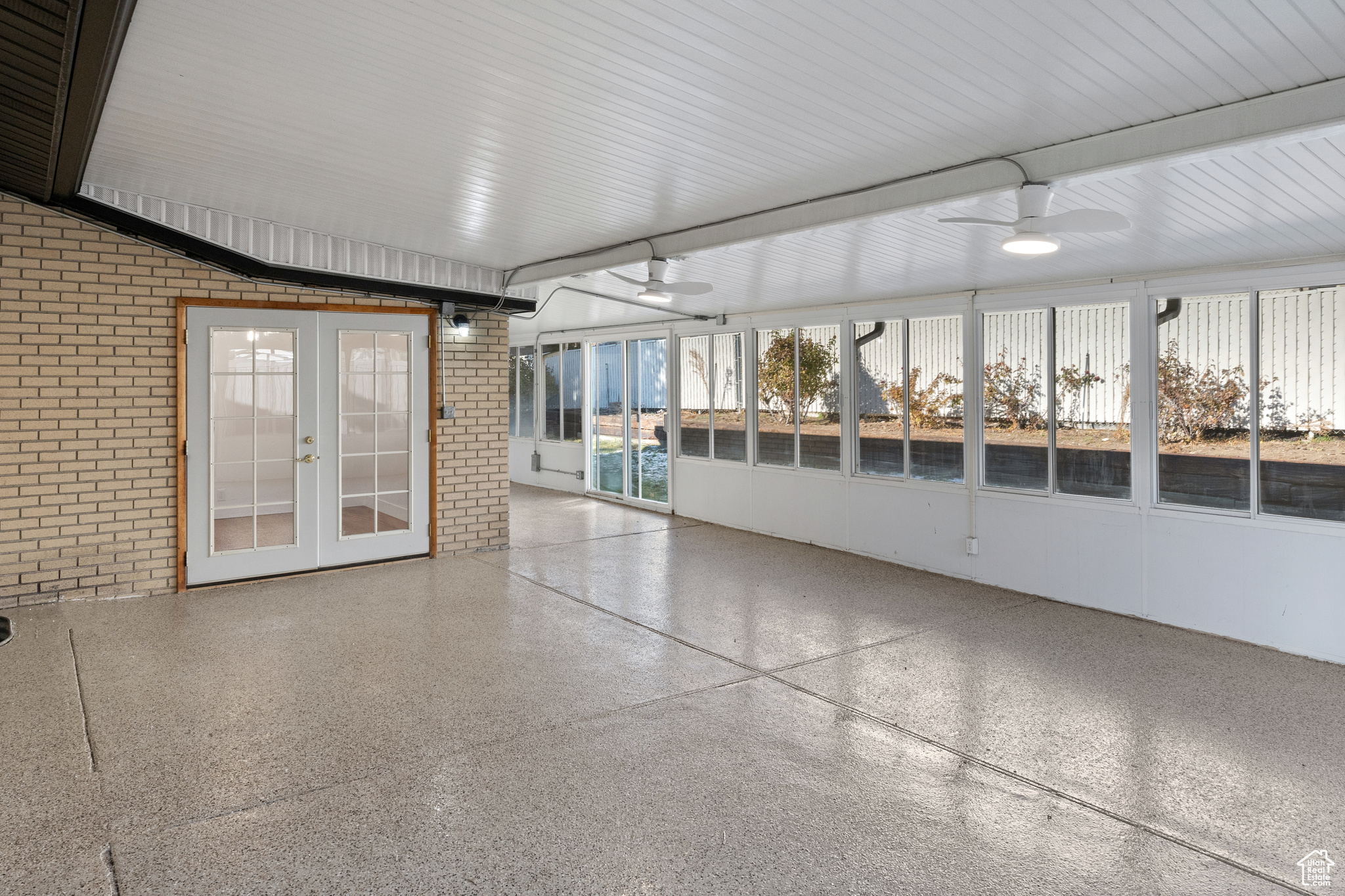 Unfurnished sunroom with ceiling fan and french doors