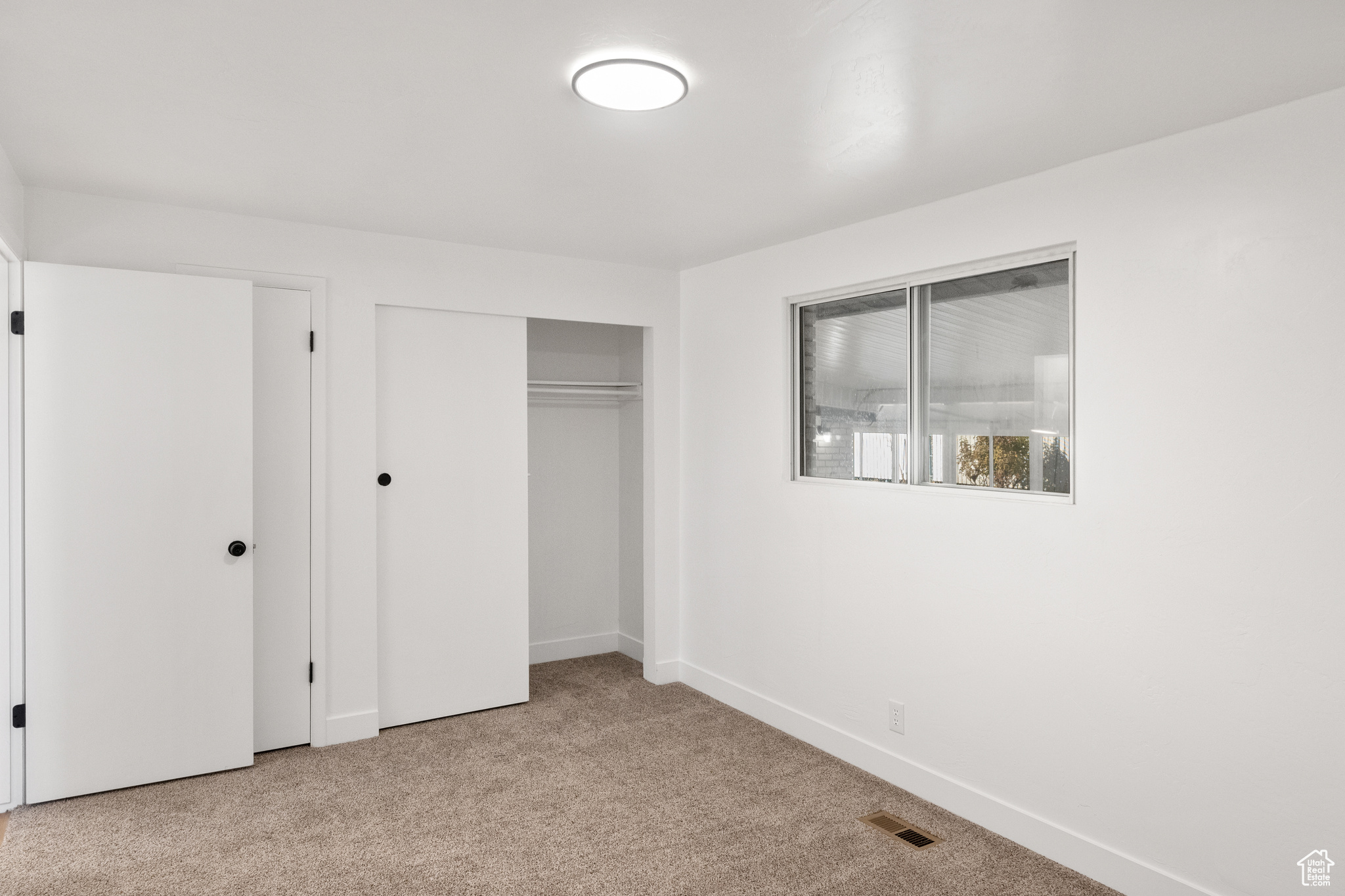 Unfurnished bedroom featuring light colored carpet and a closet