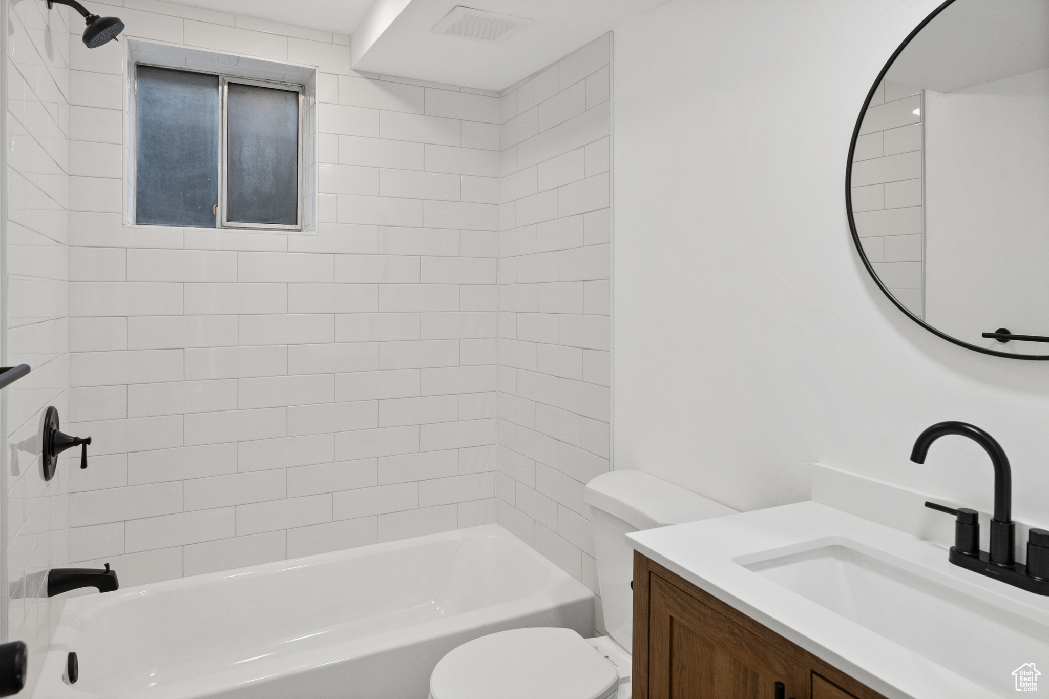 Full bathroom featuring vanity, tiled shower / bath combo, and toilet