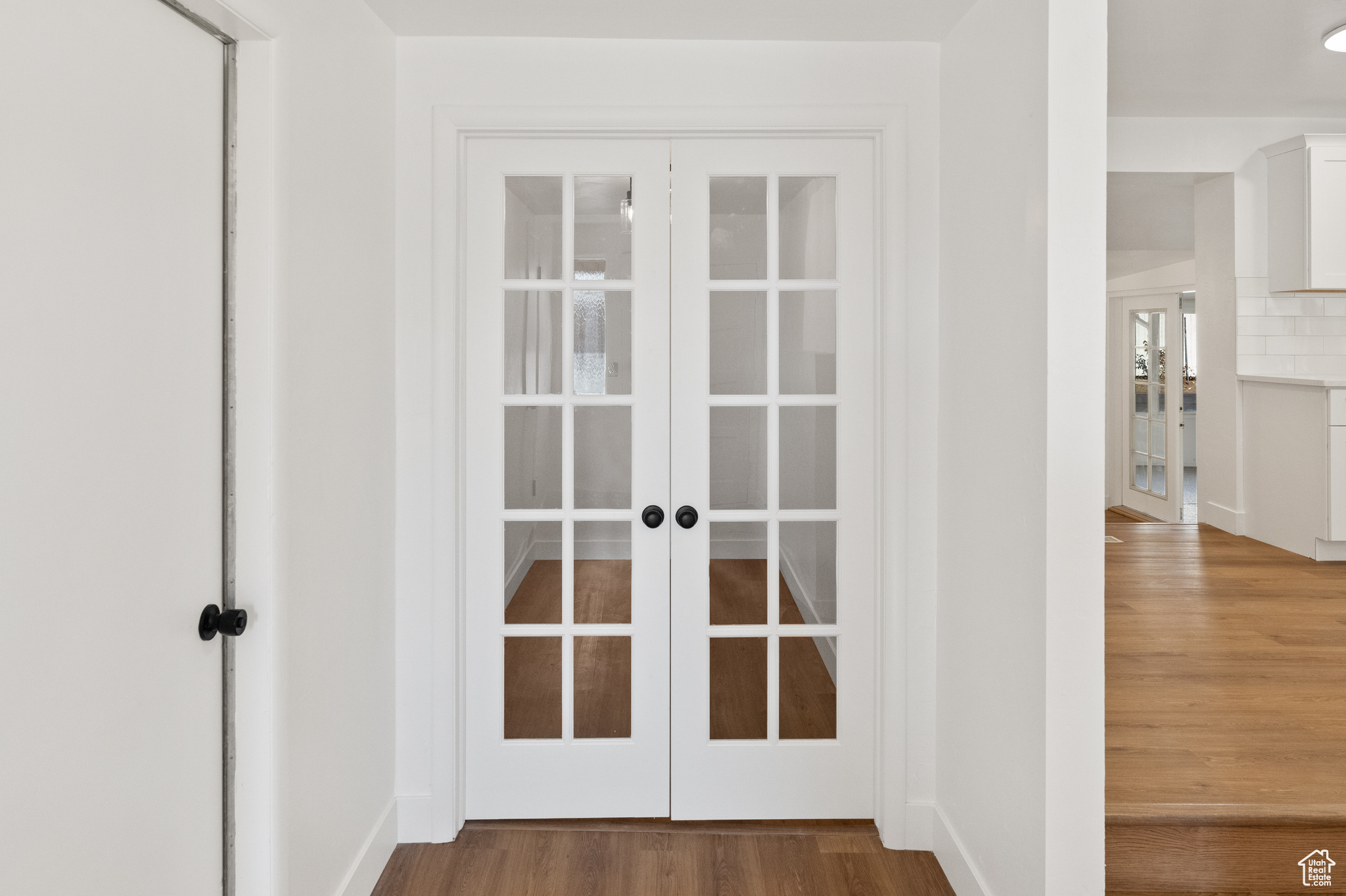 Room details with decorative backsplash, french doors, and hardwood / wood-style floors