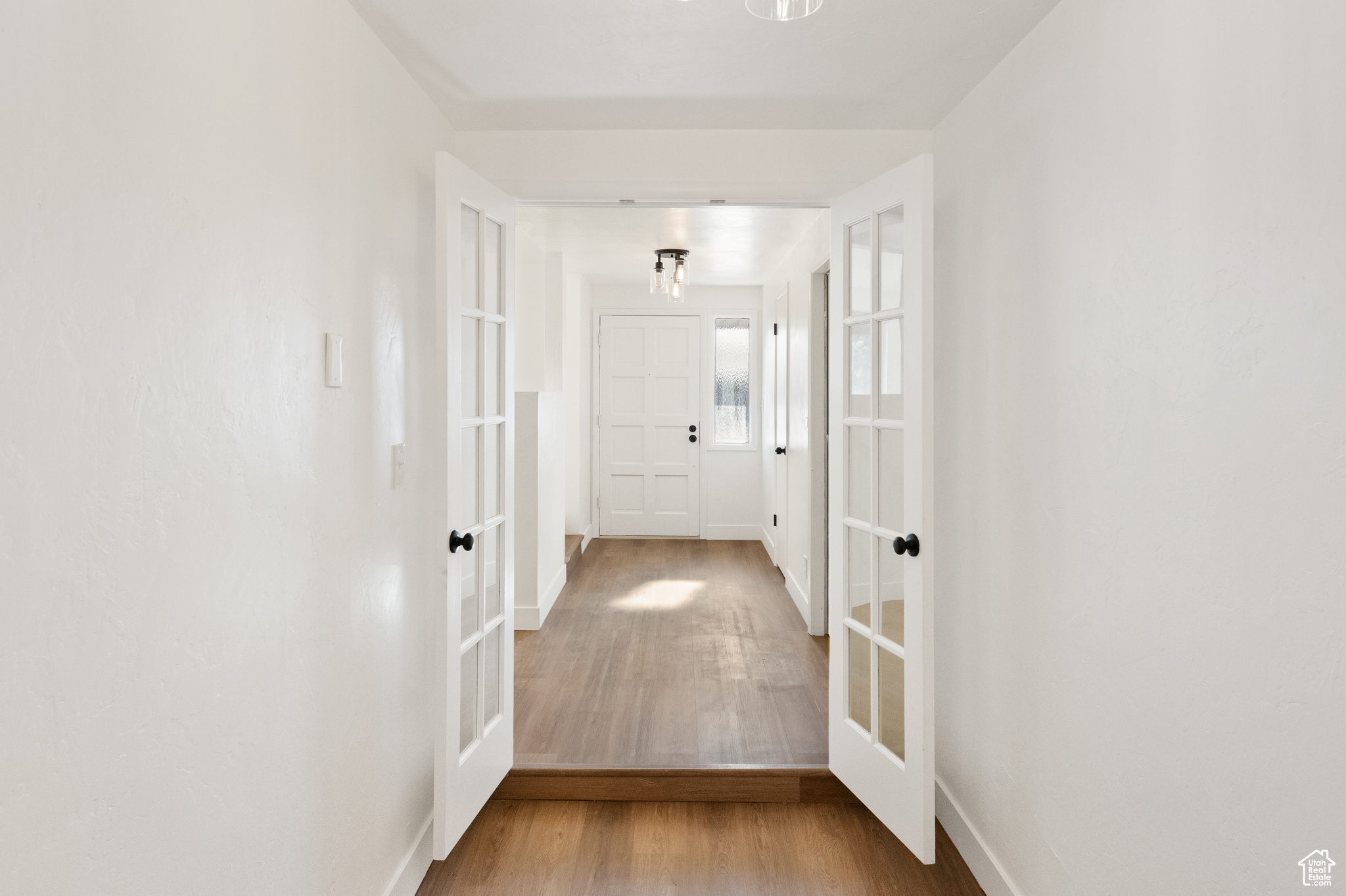 Hallway with french doors and hardwood / wood-style flooring