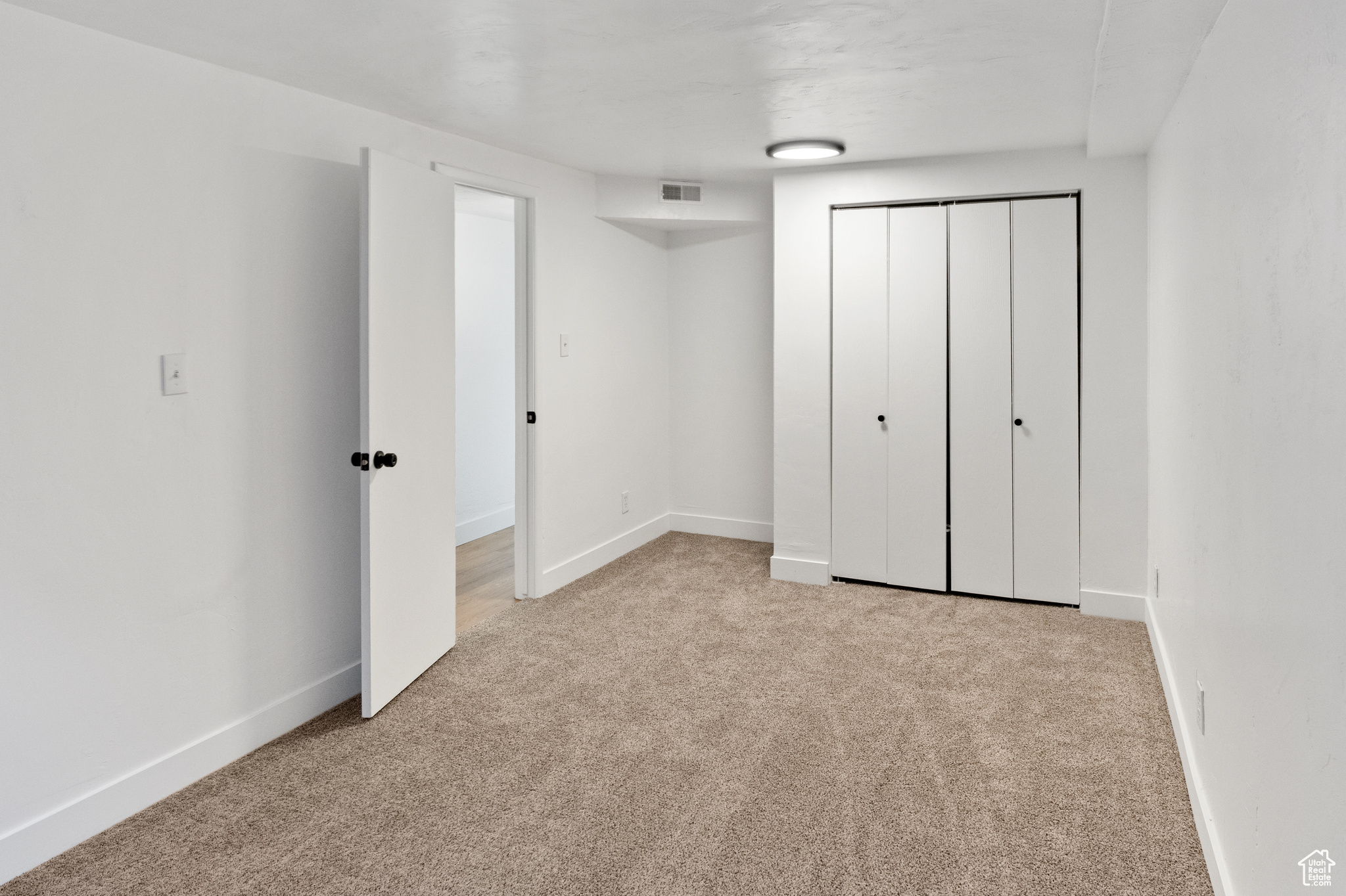 Unfurnished bedroom with light colored carpet and a closet