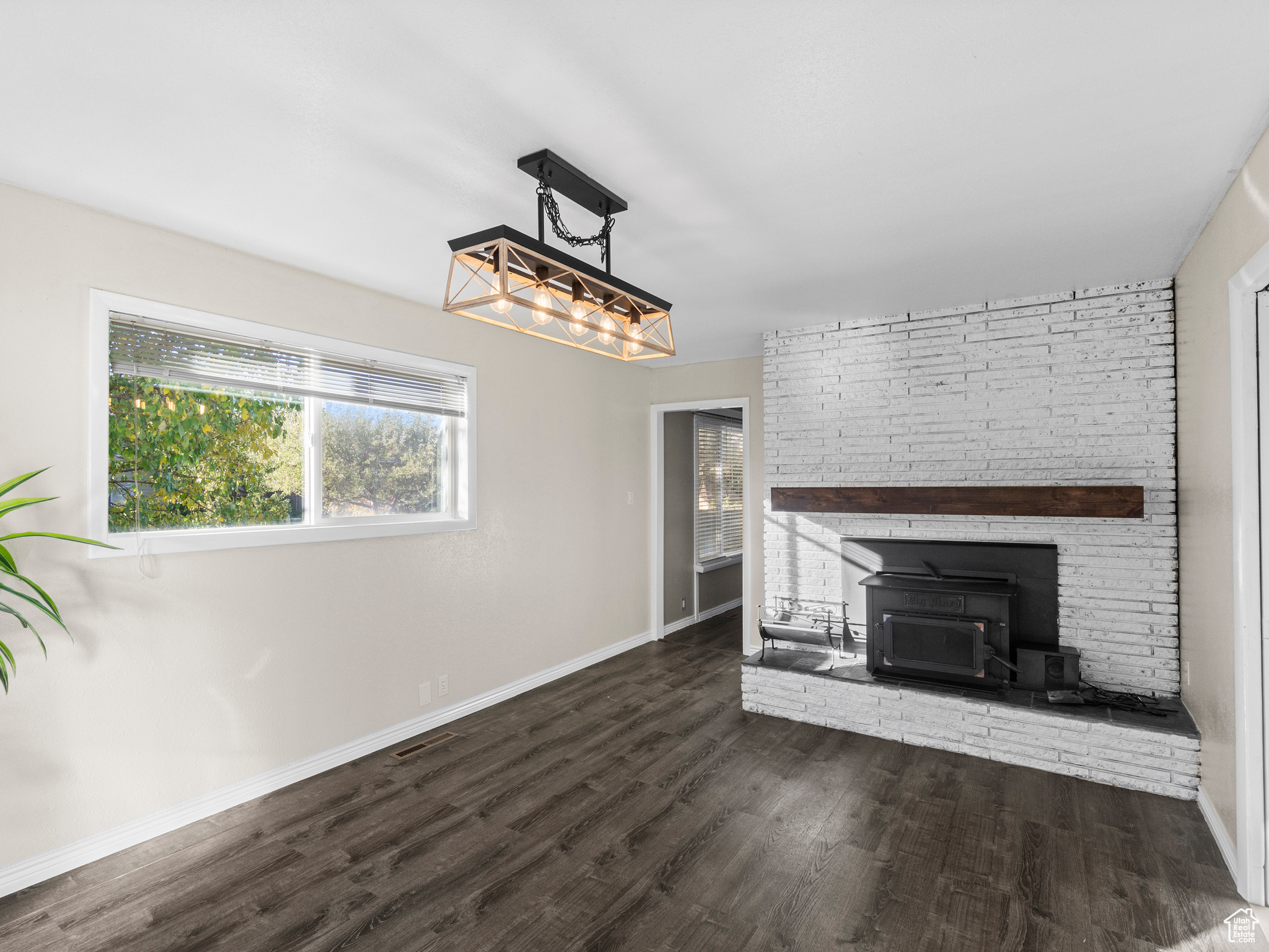 Unfurnished living room featuring a wood stove and dark wood-type flooring