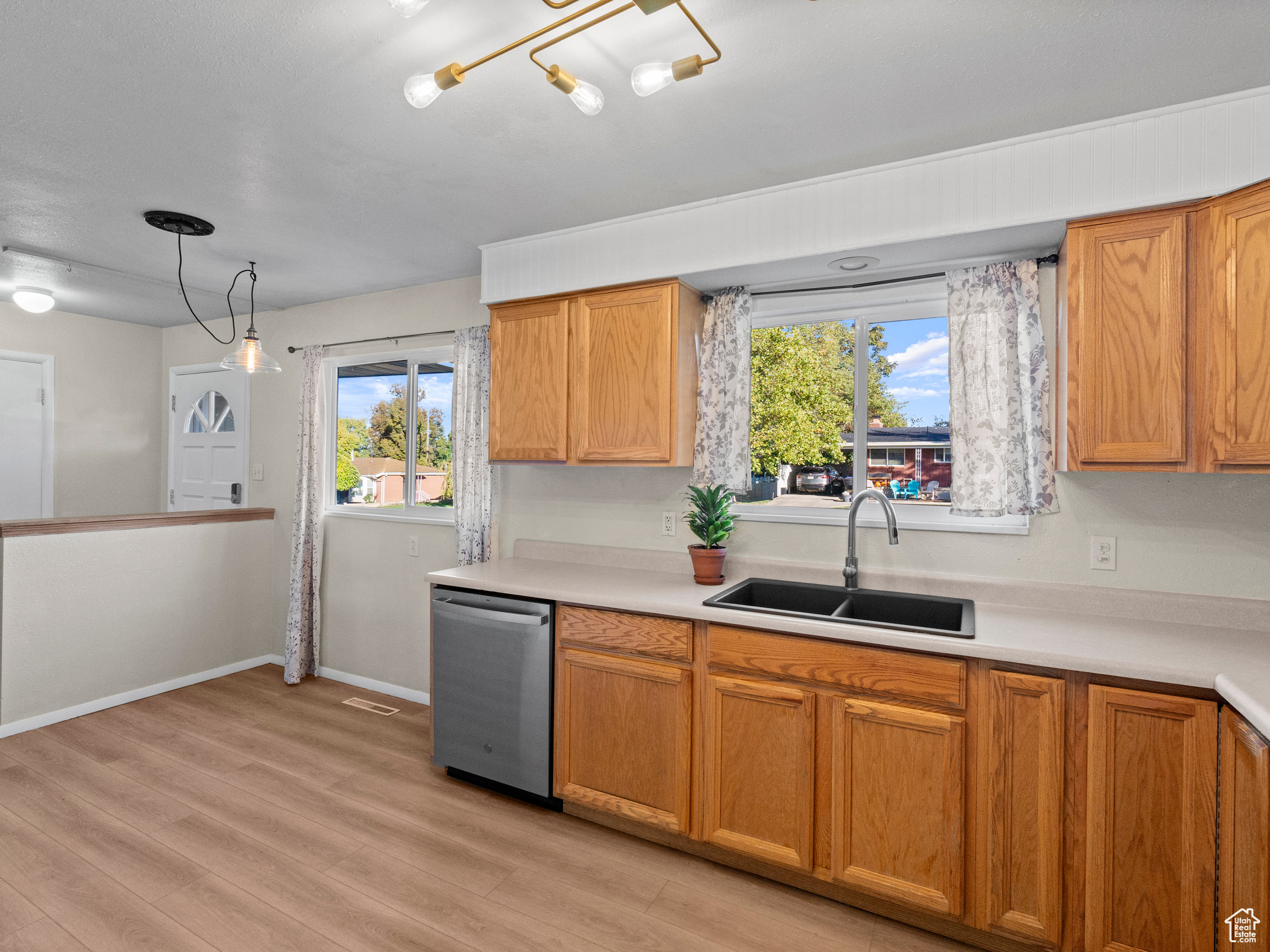 Kitchen featuring stainless steel dishwasher, plenty of natural light, light wood-type flooring, and sink