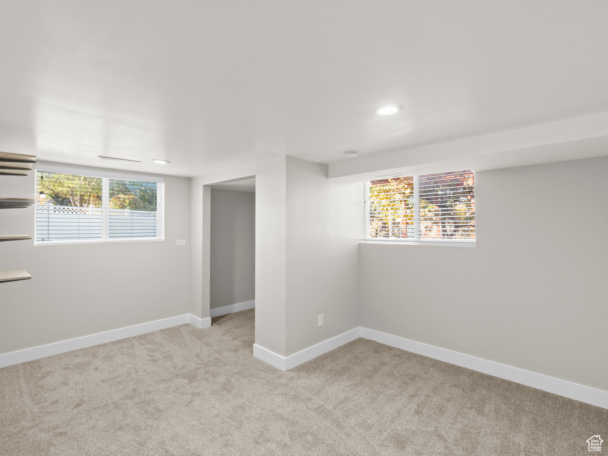 Basement with light carpet and a healthy amount of sunlight